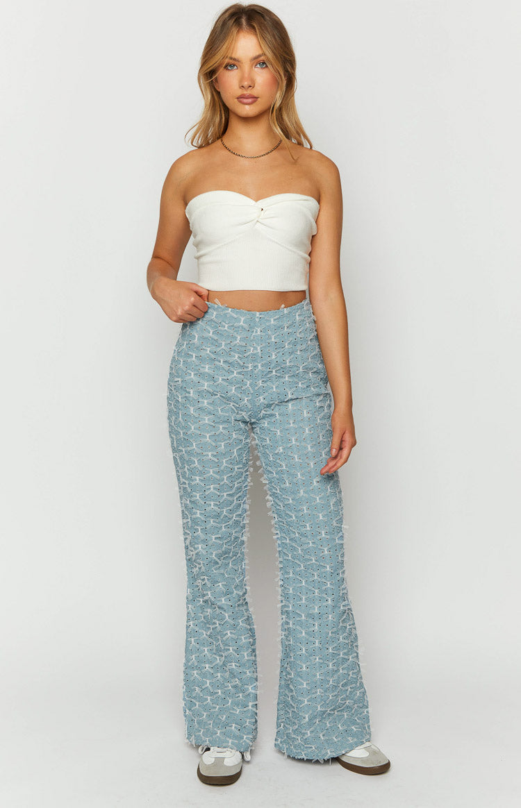 Front view of blue chambray flared jeans with an all-over bow-like textured pattern and frayed edges
