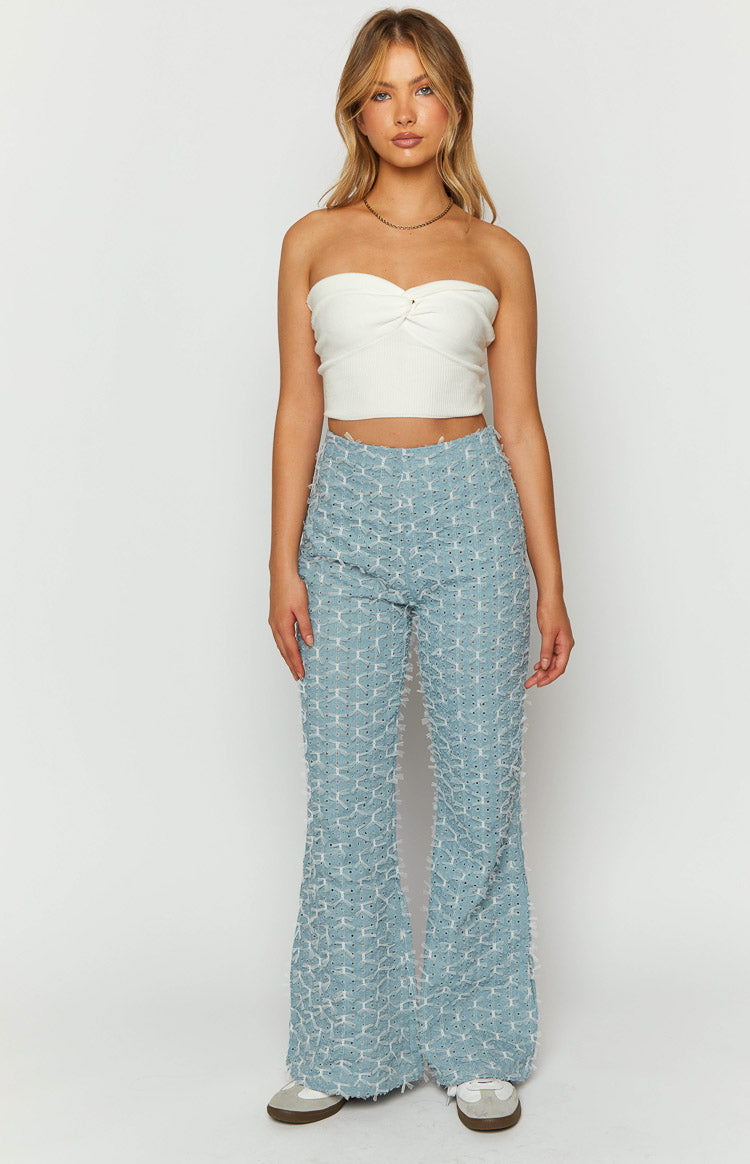 Front view of blue chambray flared jeans with a unique textured pattern of cutouts and frayed edges