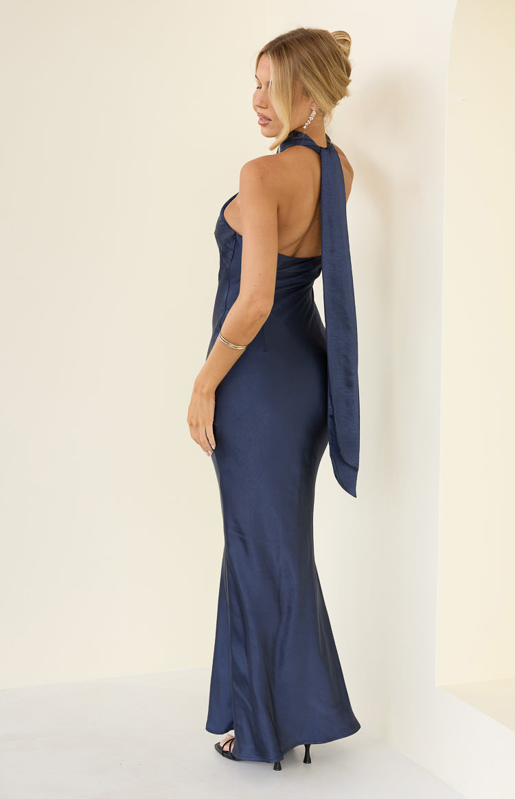 Side view of a navy satin maxi dress showing the long halter neck tie and fitted silhouette with a flared hem