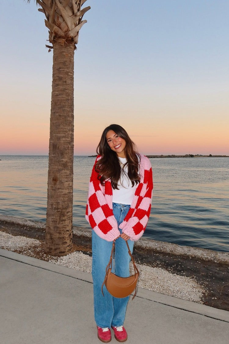 Full length view of a pink and red checkered knit cardigan with an oversized fit and long balloon sleeves