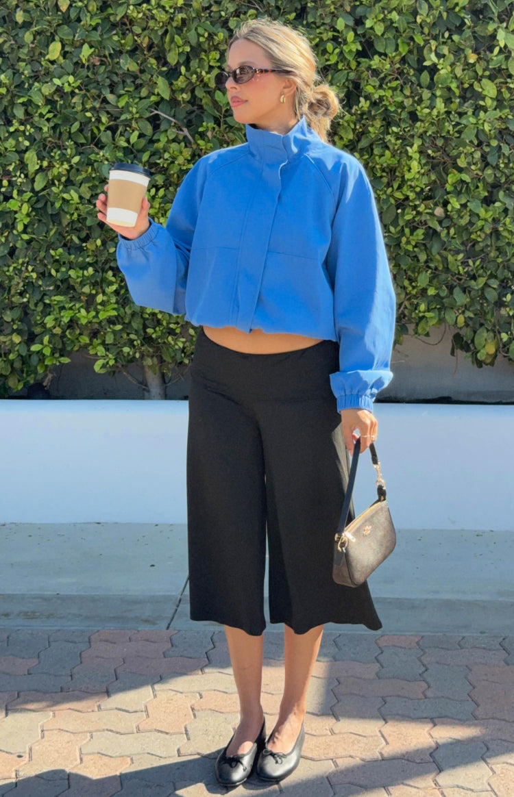 Side view of a cobalt blue cropped funnel neck sports jacket with long sleeves and elasticated cuffs