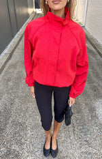 Front view of a red funnel neck sports jacket with raglan sleeves and elasticated cuffs