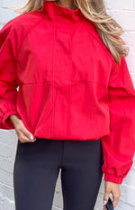 Close-up of a red crinkled nylon funnel neck sports jacket with raglan sleeves and elasticated hem