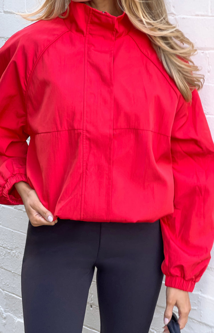 Close-up of a red crinkled nylon funnel neck sports jacket with raglan sleeves and elasticated hem