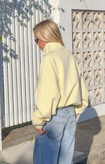 Side view of a yellow funnel neck sports jacket with oversized long sleeves and elasticated cuffs