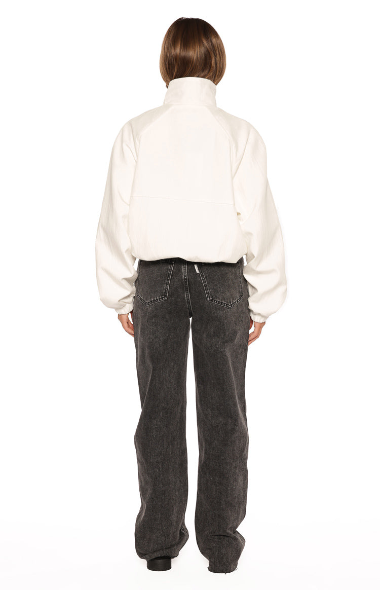 Rear view of the cream funnel neck sports jacket with raglan sleeves, a horizontal back seam, and elasticated hem