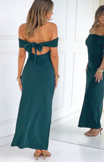 Rear view of a teal crepe off the shoulder maxi dress with a large bow tie and ruched detail on the lower back