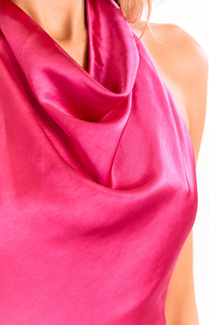 A close-up view of our model showing a hot pink satin top with a draped cowl neckline.