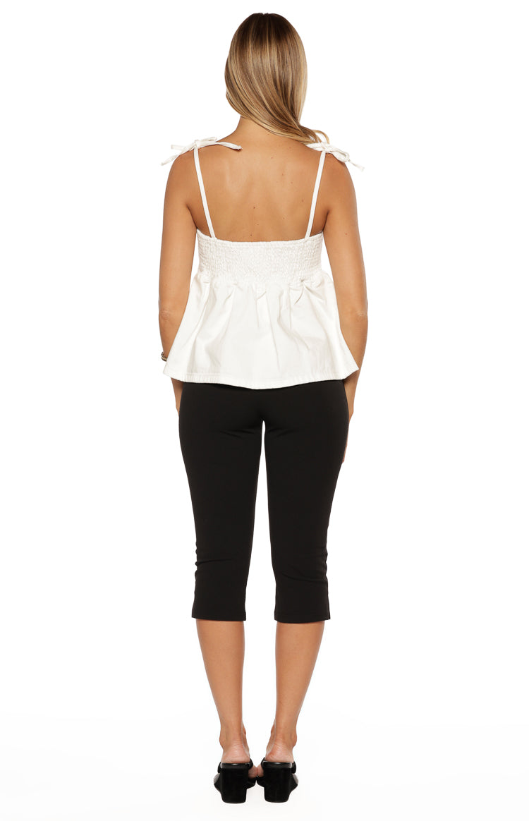 Rear view of a white denim top with tie-shoulder straps and a shirred back panel