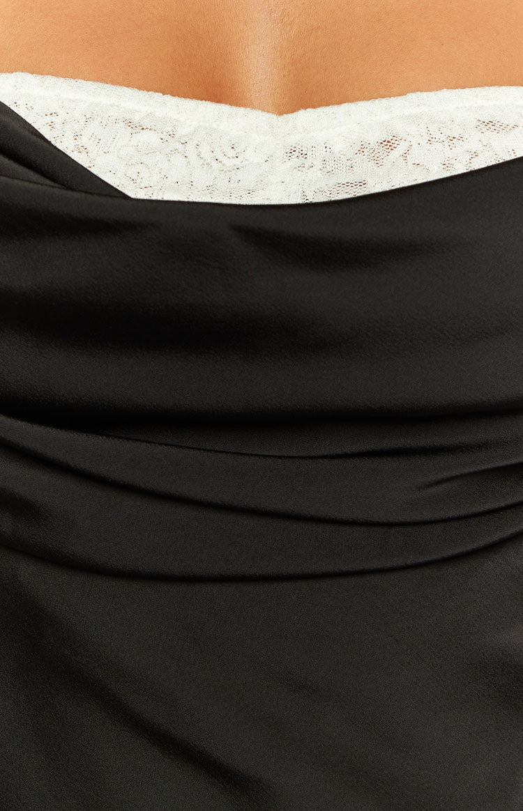 Close-up of the white lace trim peeking from under the draped black satin of a maxi dress