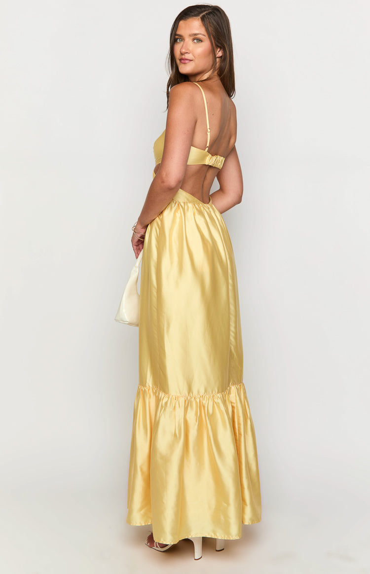 Side view of a yellow maxi dress with a bra-style back, waist cutouts, and a gathered ruffle hem