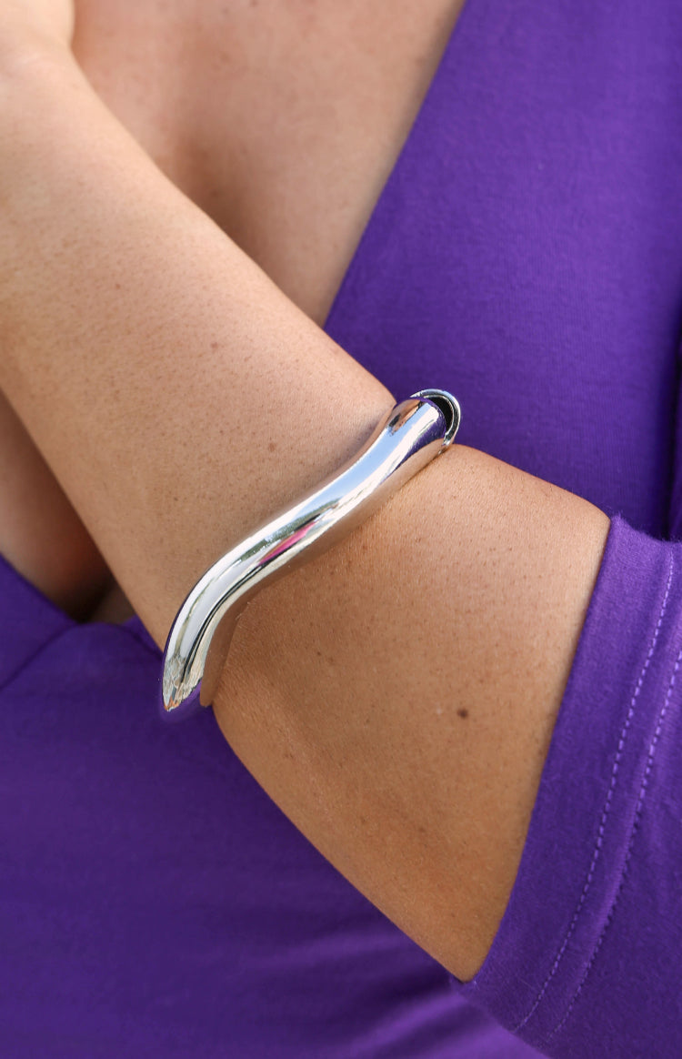 Close-up of the polished silver wavy cuff bracelet, highlighting its sculptural, open design