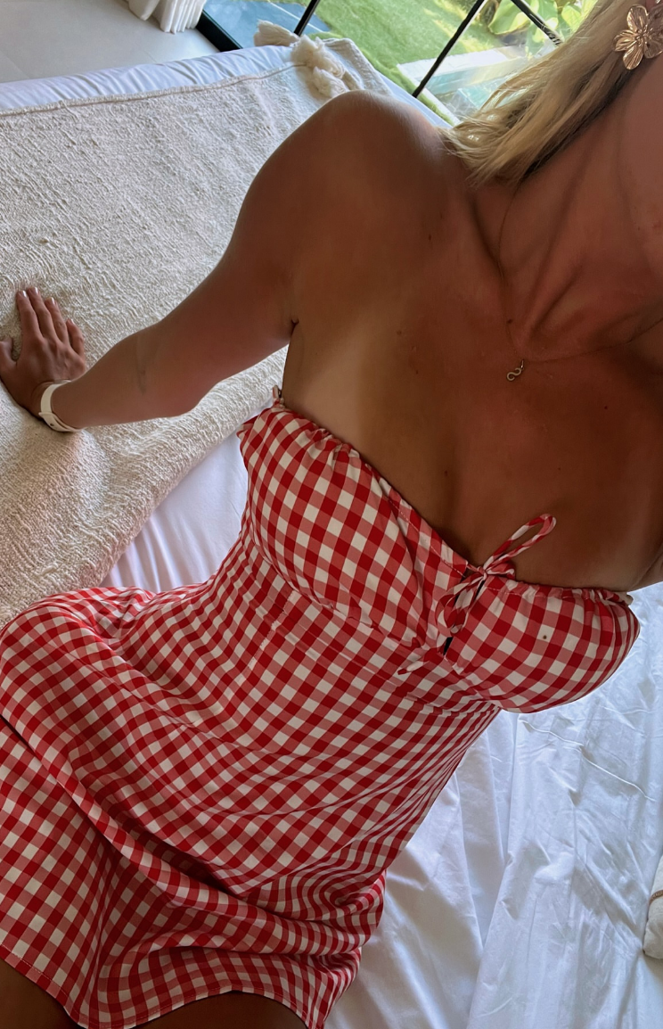 Close-up of the red gingham strapless mini dress showing the ruched bust and tie-front detail