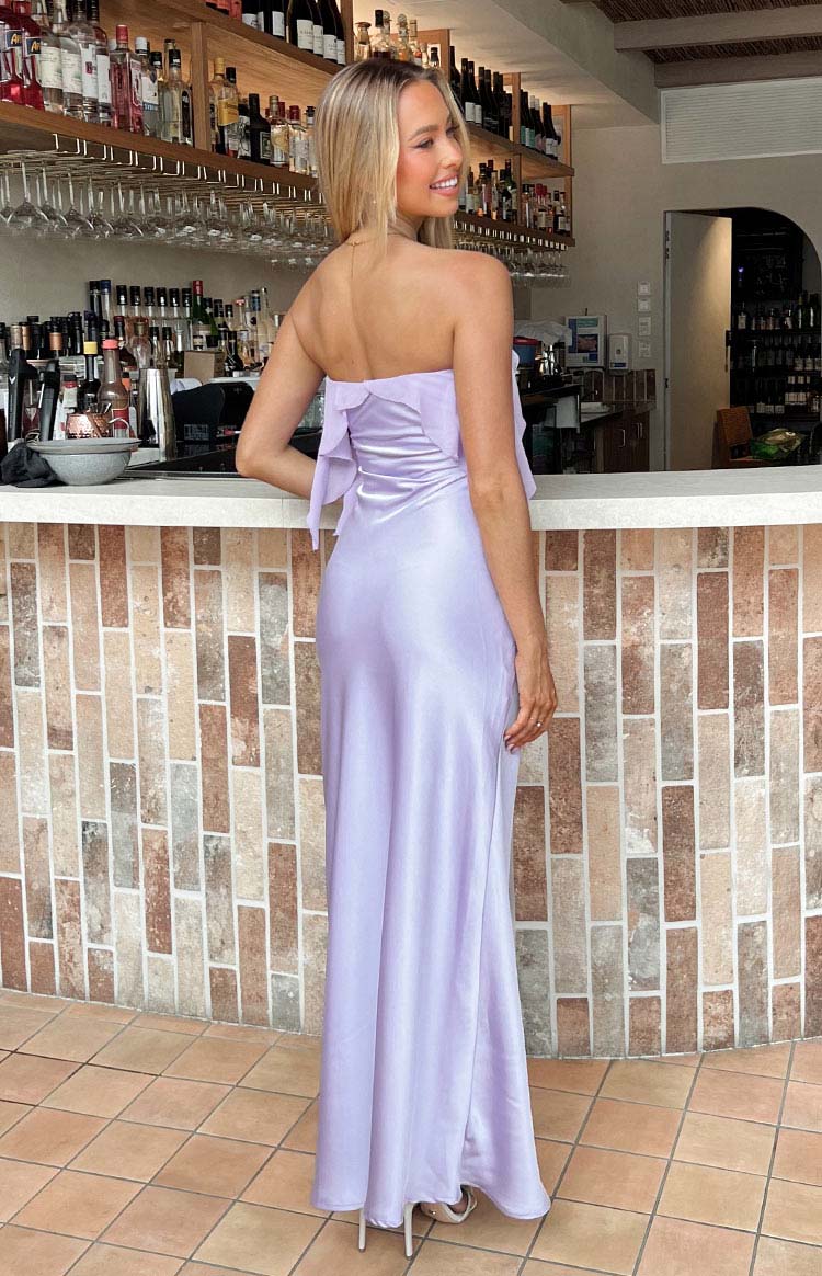 Rear view of a purple strapless maxi dress with a ruffle detail across the back bodice and a flowing skirt