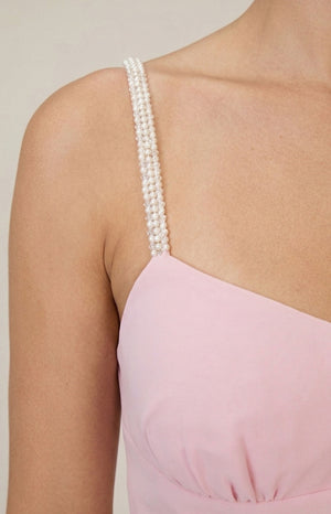 Close-up of the multi-strand pearl shoulder strap and gathered pink fabric of the maxi dress