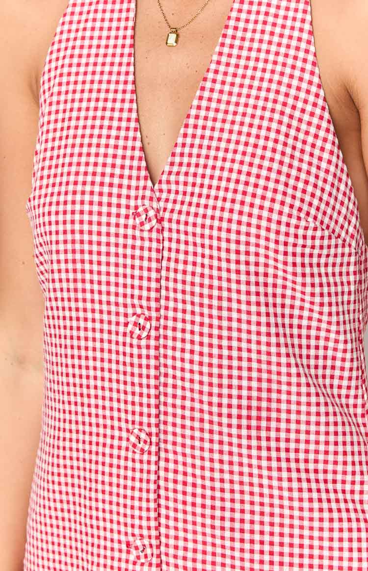 Front close-up showing the deep V-neckline and decorative fabric-covered buttons of the red gingham mini dress