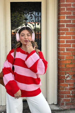 Red and pink stripe knit sweater with an off shoulder neckline and voluminous long sleeves