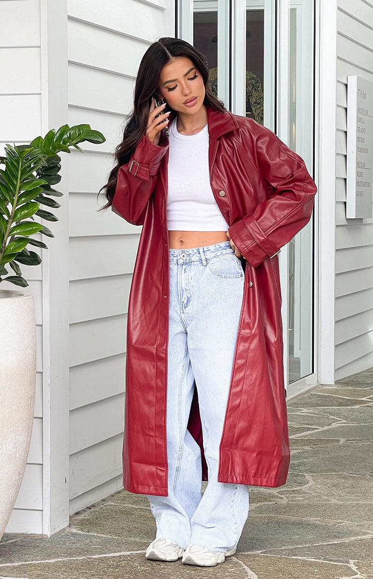 Full length view of a red PU trench coat worn open, showing its relaxed fit and longline silhouette