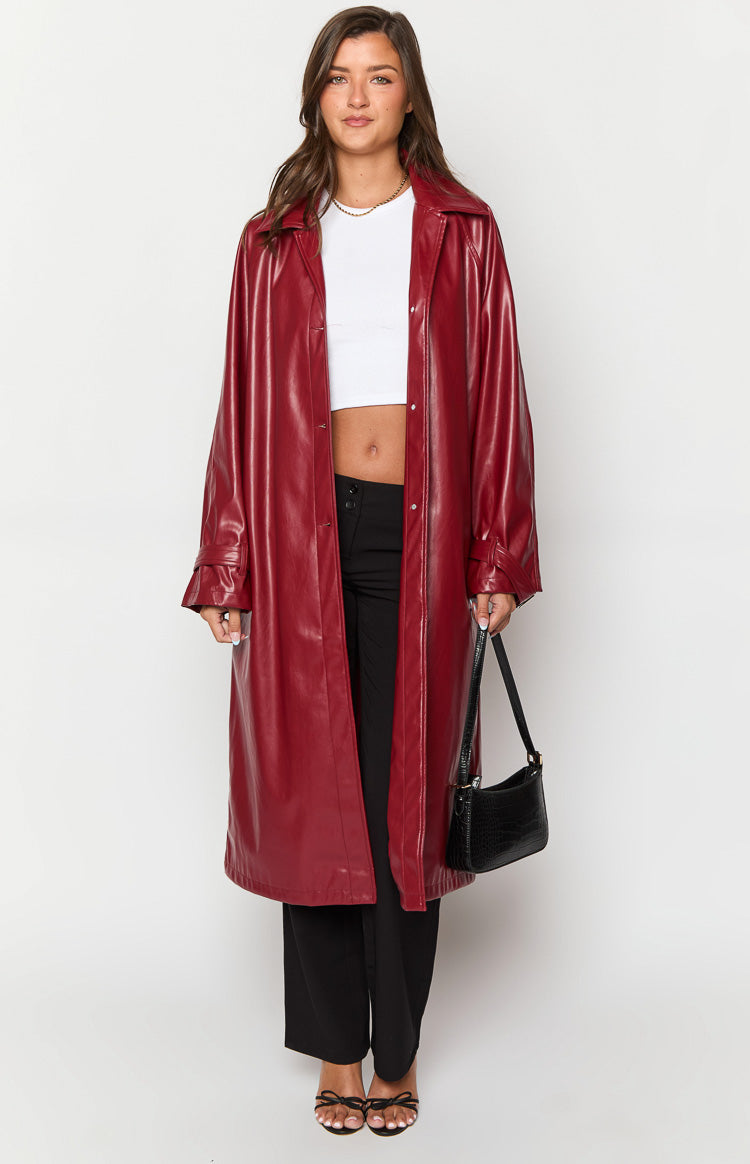 Front view of a red faux leather trench coat with a wide collar and cuff straps, open to reveal its relaxed fit and longline length