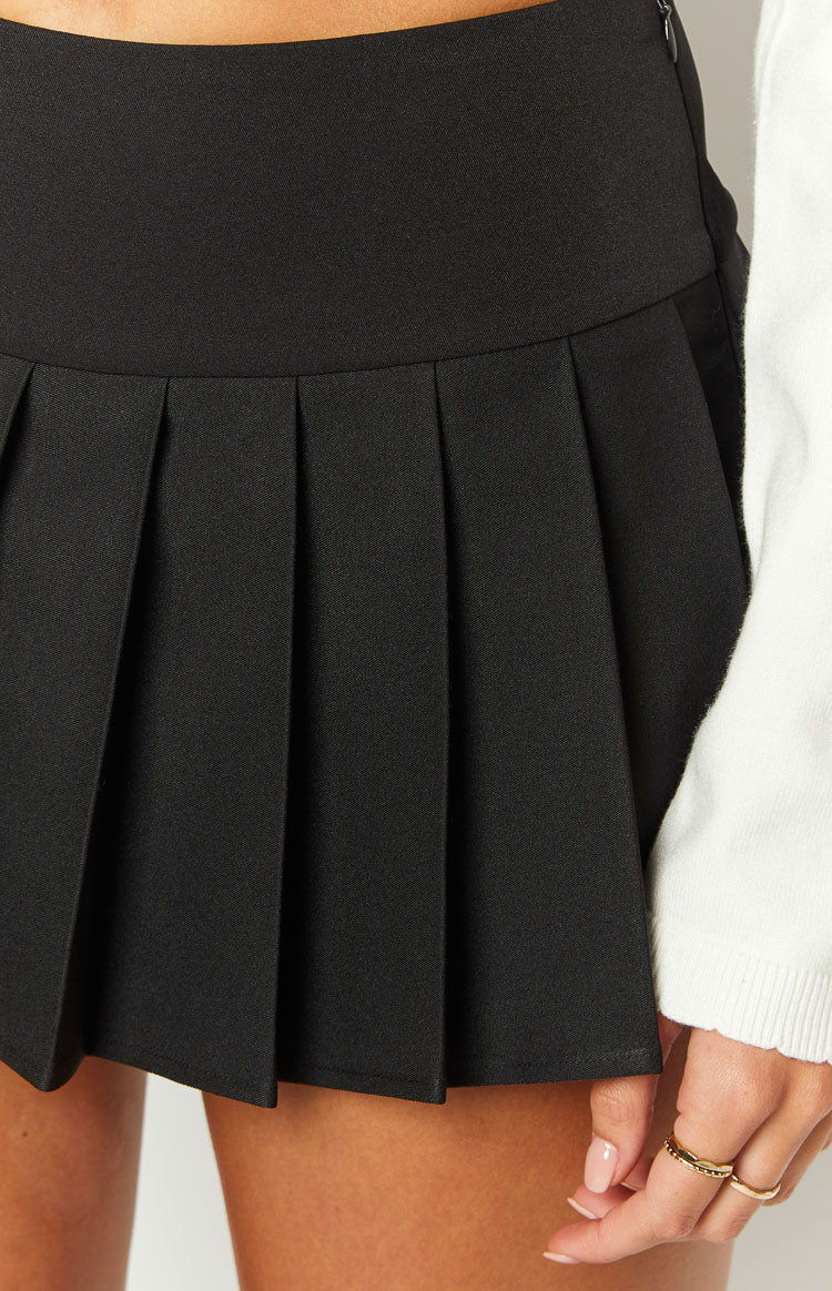 Close-up of the black pleated mini skort showing the flat waistband and side zipper
