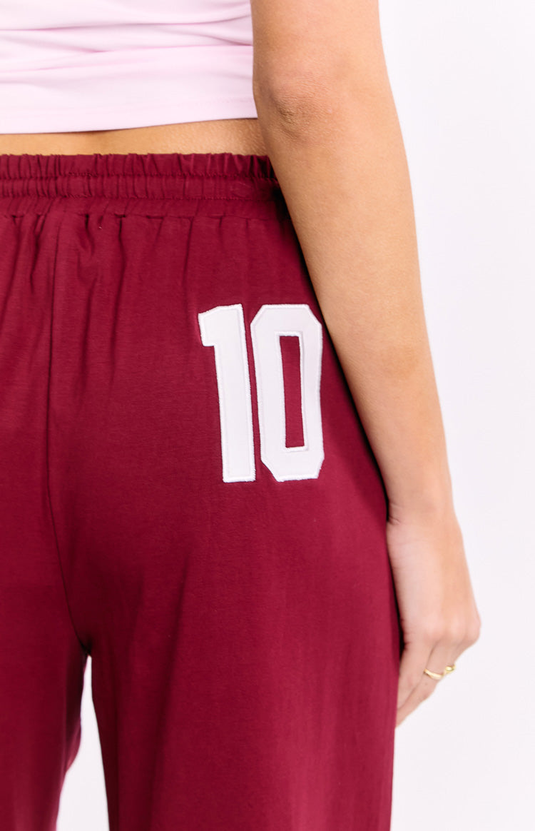 Close-up of the white '10' applique and elasticated waistband on burgundy pants