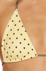 Close-up of the yellow triangle bikini top showing brown polka dots and ruched bottom edge