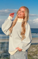 Blue and white striped sweater with a cream ribbed mock neck, cuffs, and hem, showing a relaxed fit