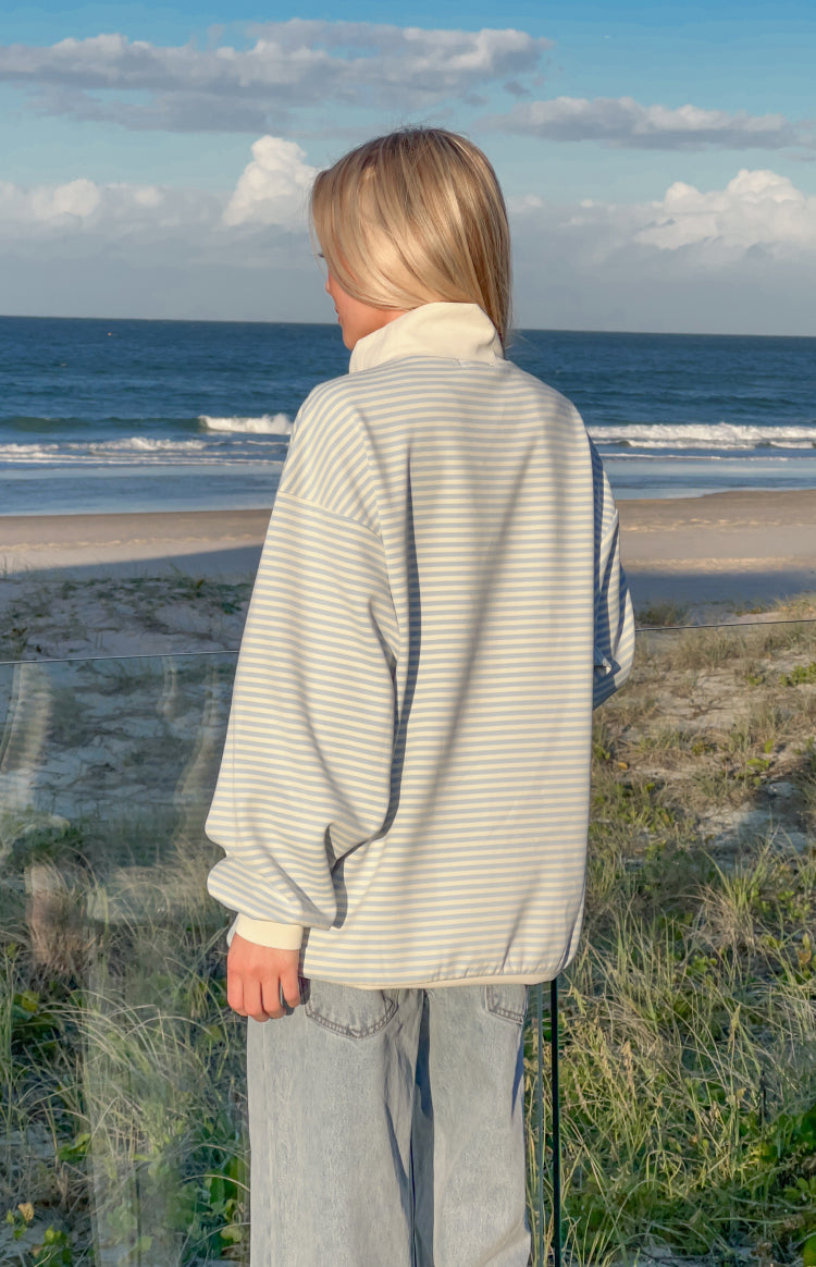 Rear view of a blue stripe mock neck sweater with a cream collar, relaxed fit, and ribbed cuffs and hem