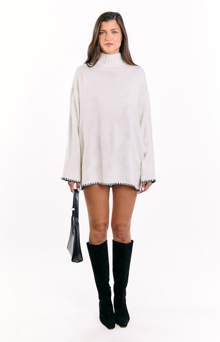 Oversized cream mock neck sweater dress with long sleeves and black whipstitch detail on hem and cuffs