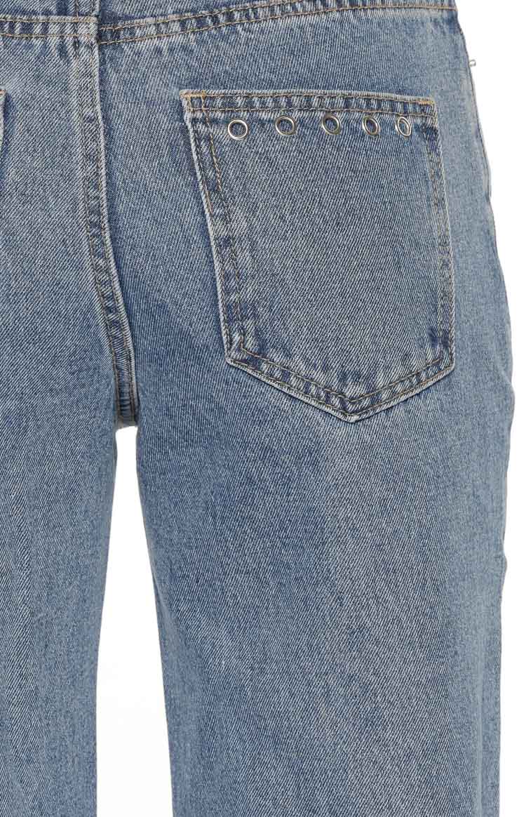 Back pocket detail of mid-wash jeans with a row of silver eyelets