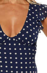 Close-up of the navy polka dot mini dress showing the V-neckline, gathered bust, and flutter sleeve
