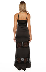 Rear view of a black satin maxi dress with thin spaghetti straps and two sheer lace insert panels on the skirt