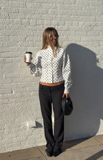 White polka dot jacket with a high neck, long voluminous sleeves, and a cropped button-front hem