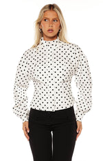 White polka dot jacket with a high neck, button-front, fitted waist, and voluminous puff sleeves