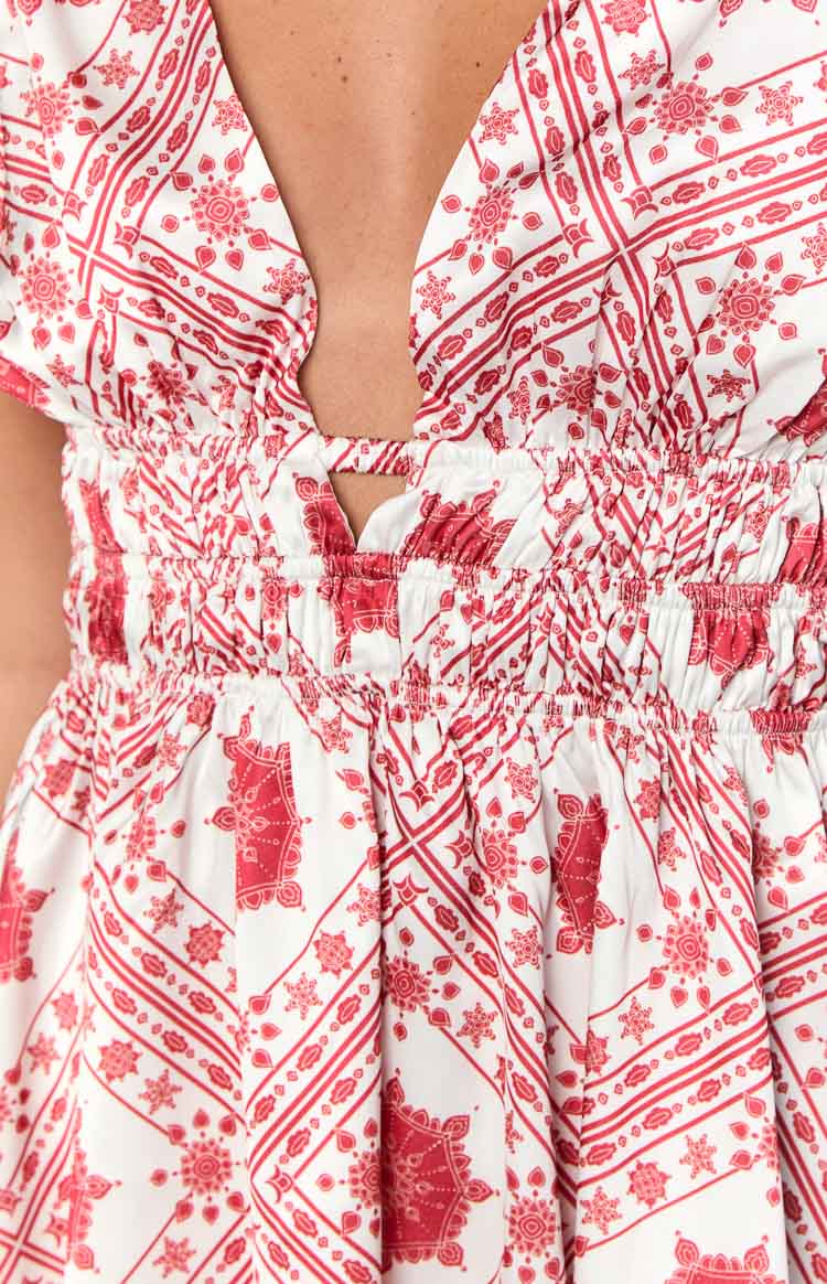 Close-up of the red tile print mini dress showing the deep V-neckline with a small cutout and shirred elastic waist