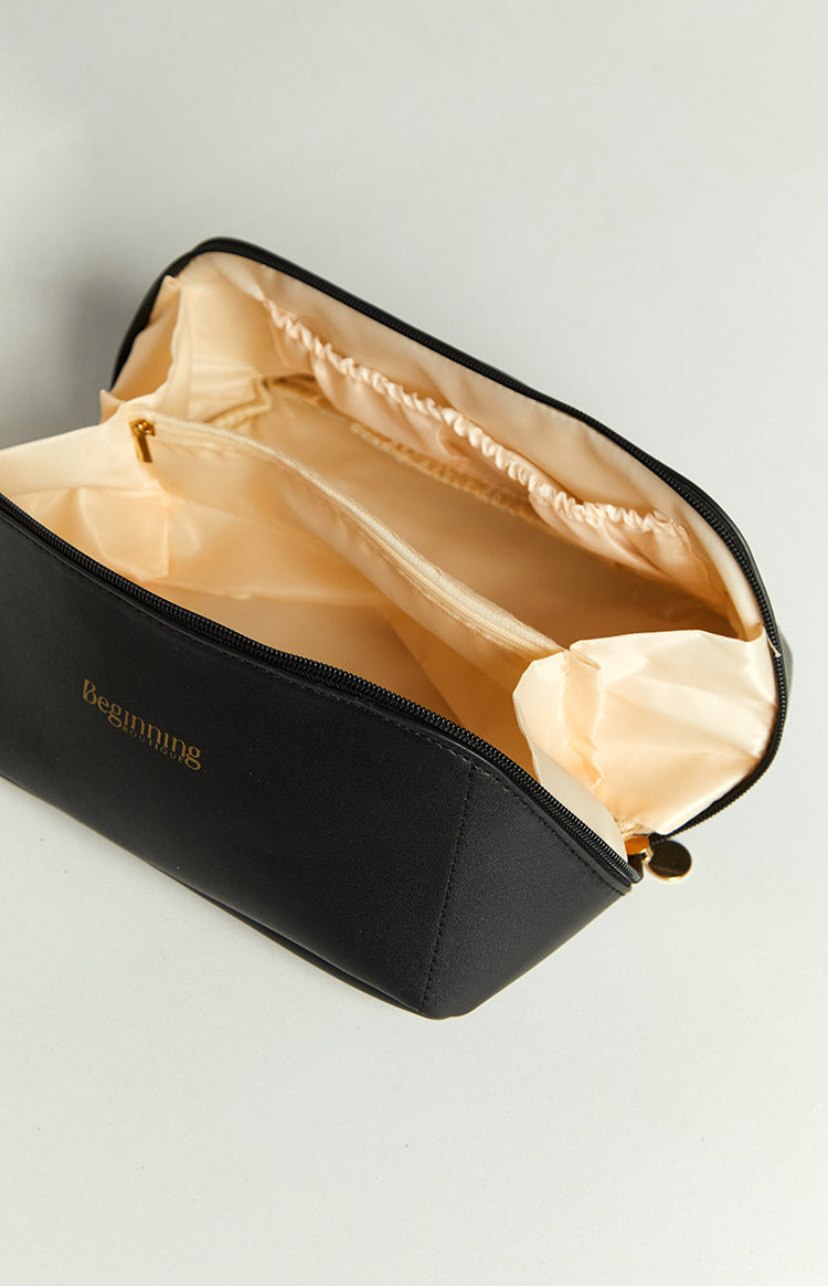 Open black cosmetic bag with light beige satin lining, featuring an internal zippered pocket and elasticated side compartments