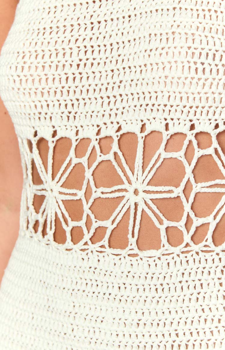 Close-up of the cream crochet mini dress showing the open-knit floral pattern detail at the waist