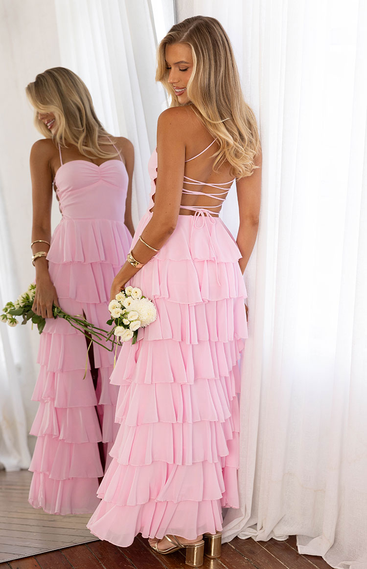 Back view of a pink maxi dress with a criss-cross lace-up back, side cutouts, and a full tiered ruffle skirt