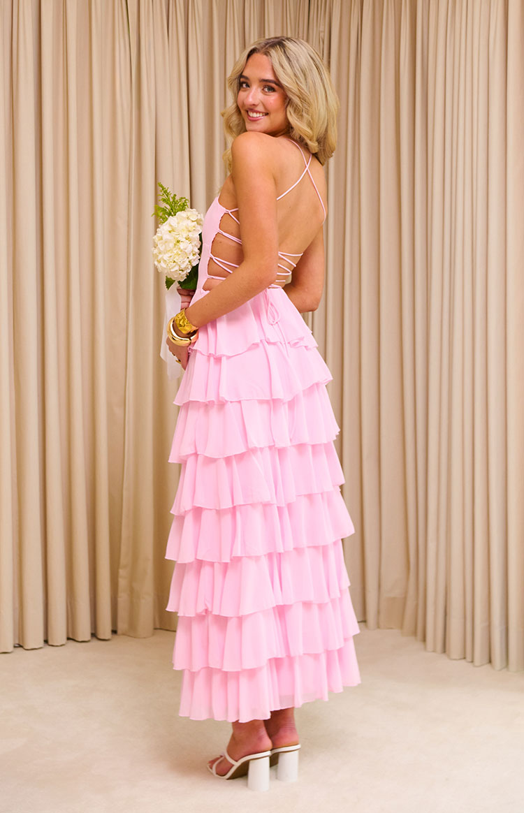 Side view of a pink ruffle maxi dress with criss-cross back straps, side cutouts, and tiered skirt