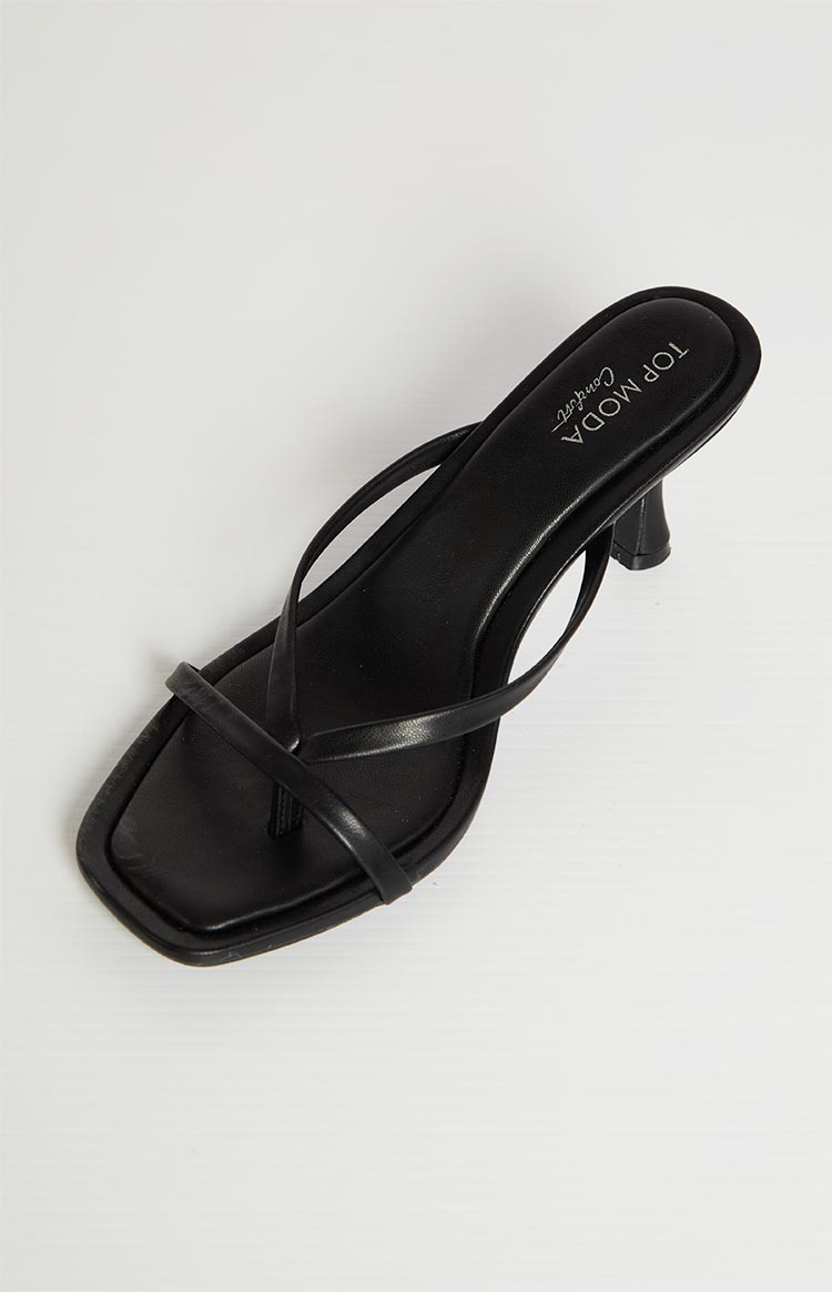 A single black heeled sandal with thin straps is shown on a light background. The sandal has a square toe and a small, curved heel.