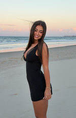 Side view of a black polka dot mini dress with a deep V-neckline and delicate lace trim