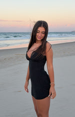 Side view of a black polka dot mini dress with a fitted silhouette and lace trim V-neck