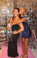 Side view of a navy satin mini dress with a fitted bodice, ruffled shoulder, and flared mini skirt