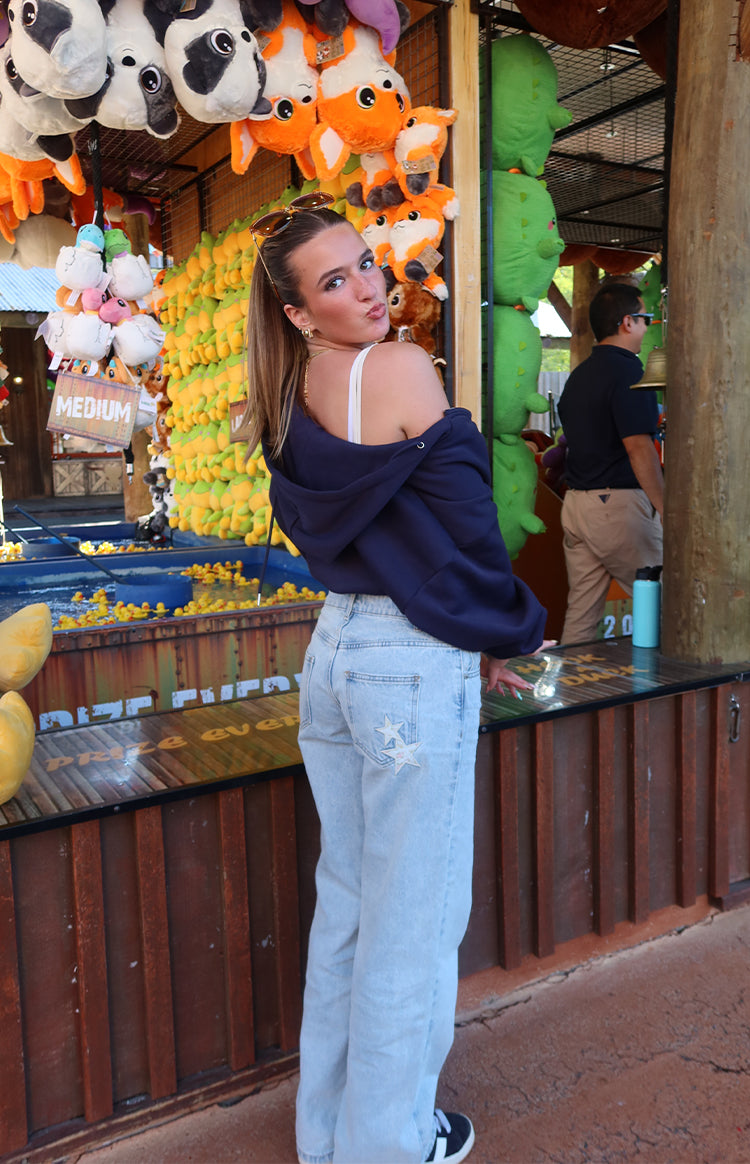 Rear view of light wash baggy leg jeans with white star embroidery on the back pocket