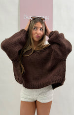 Chocolate brown chunky knit cardigan with a wide boat neckline worn off-shoulder and voluminous long sleeves