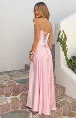 Rear view of a pink satin strapless maxi dress with a lace-up corset back and flowing skirt