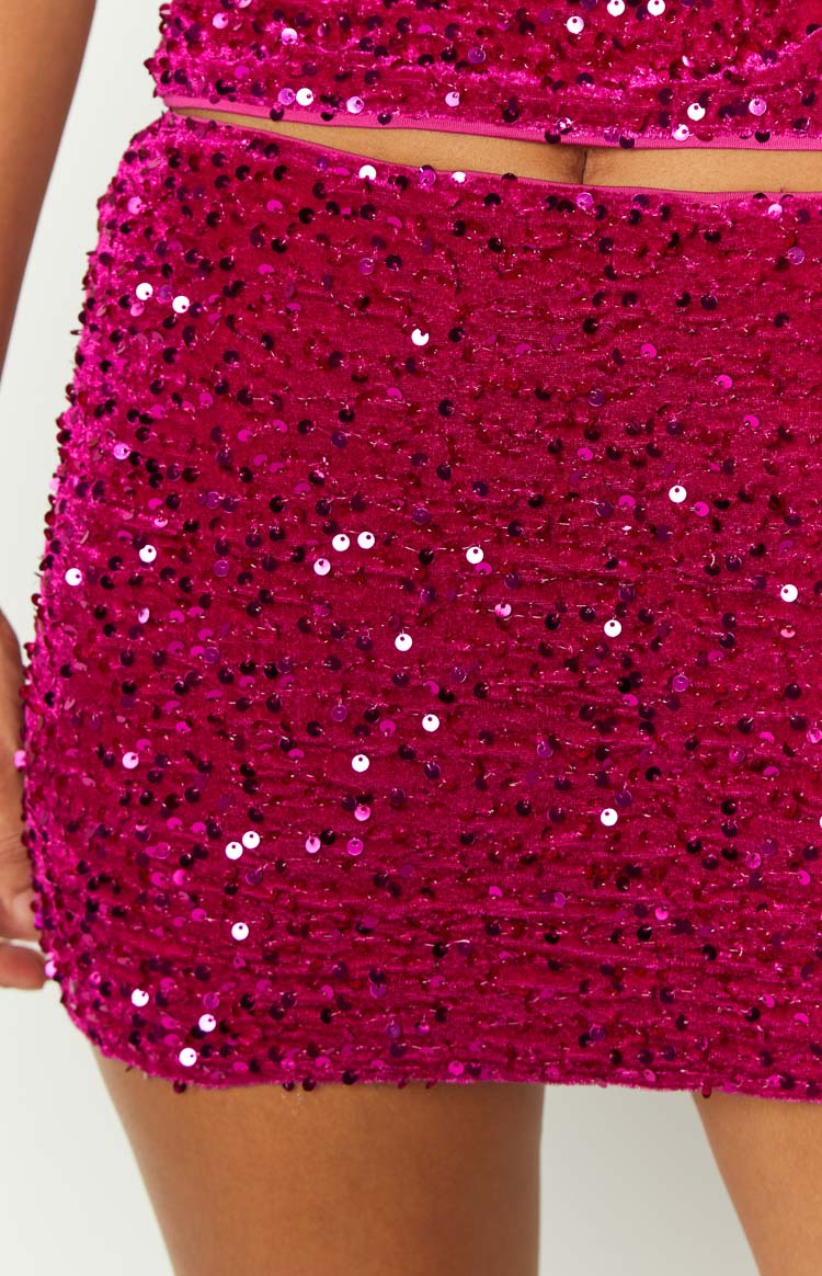 Close-up of the magenta mini skirt's sequin fabric, showing the dense, varied sequins on a textured base