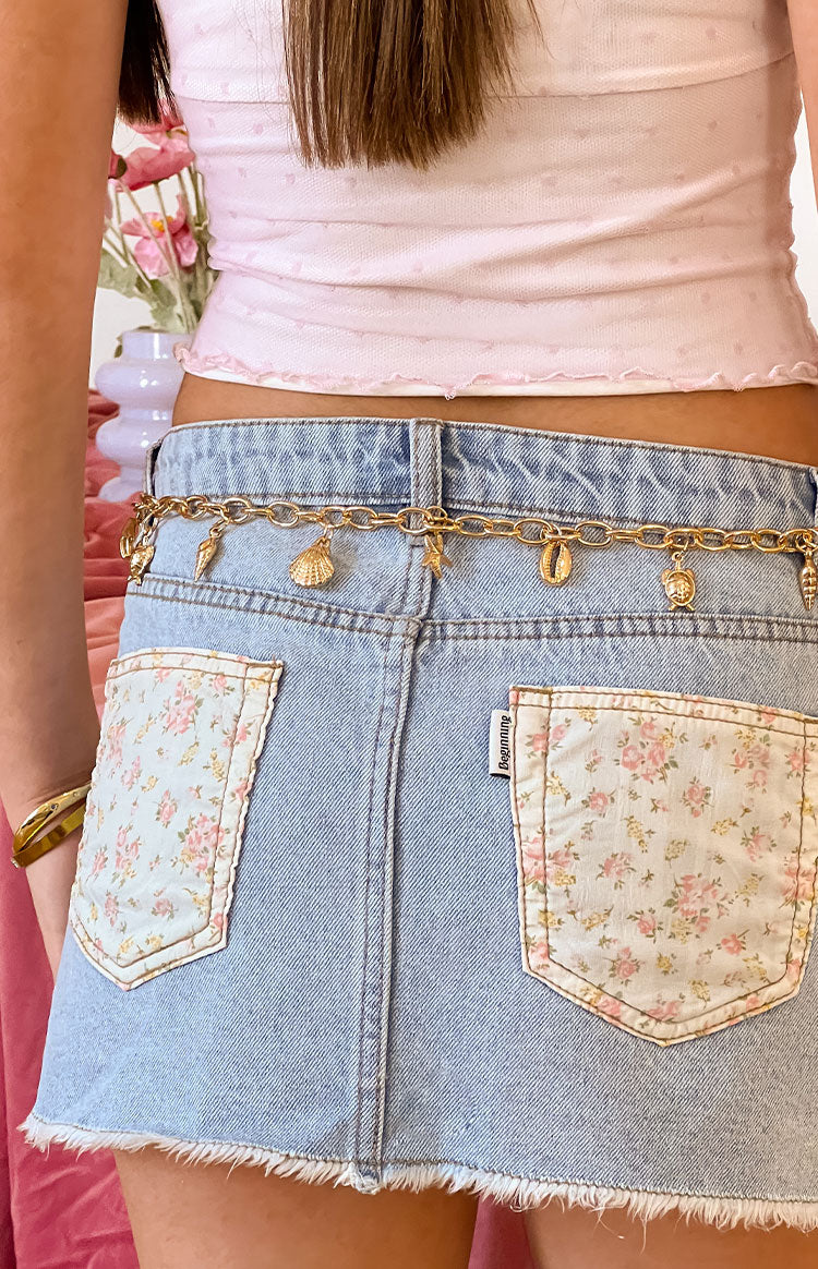 Rear view of a gold chain belt with multiple shell and sea-themed charms including a starfish, turtle, and various shells