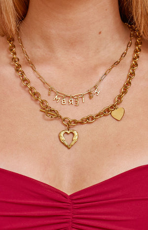 A chunky gold-toned necklace featuring a toggle clasp and an open heart pendant accompanied by a smaller solid heart charm.