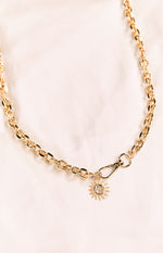 Close-up of the gold chain belt's carabiner clip and the detailed sun and moon charm
